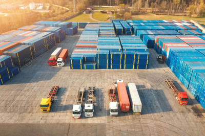 日落时卡车和集装箱的鸟瞰图。用于进出口的物流码头的自动卡车、集装箱仓库的顶视图。商业。货物运输。航运和货物。行业